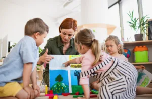 Educator guiding infants and toddlers during a hands-on art activity at a daycare for infants and toddlers, supporting creativity, early learning, and social development in a safe classroom environment.