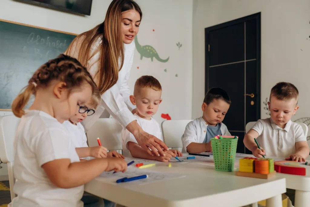 Educator guiding young children during a creative learning activity at a daycare in Langley, supporting early childhood development in a safe classroom setting.