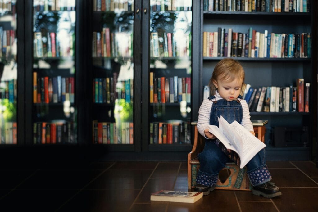 A young child sitting in a cosy reading space, flipping through a book independently—an example often considered when parents think about what age to preschool and early learning readiness.