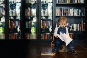 A young child sitting in a cosy reading space, flipping through a book independently—an example often considered when parents think about what age to preschool and early learning readiness.