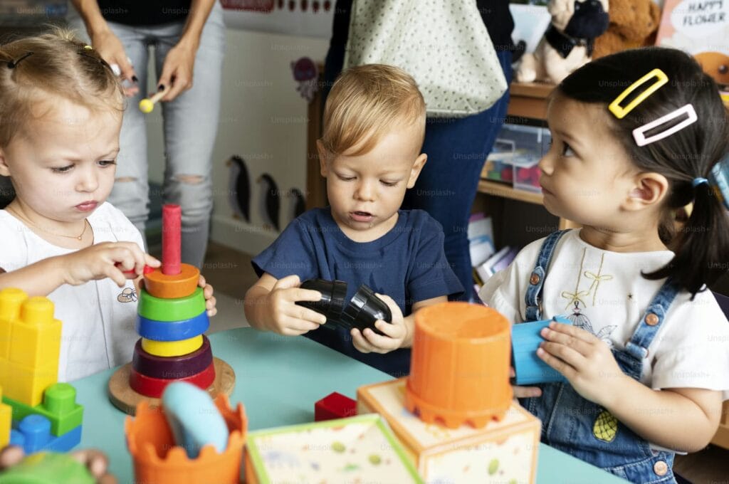 Children engaging with colorful stacking toys and blocks in an educare daycare setting, guided by caregivers to support early learning and development.