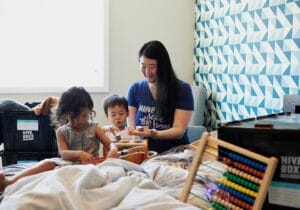 A caregiver engaging young children in hands-on learning activities with toys and blocks, showcasing a warm and interactive kiddie daycare environment that supports early development.