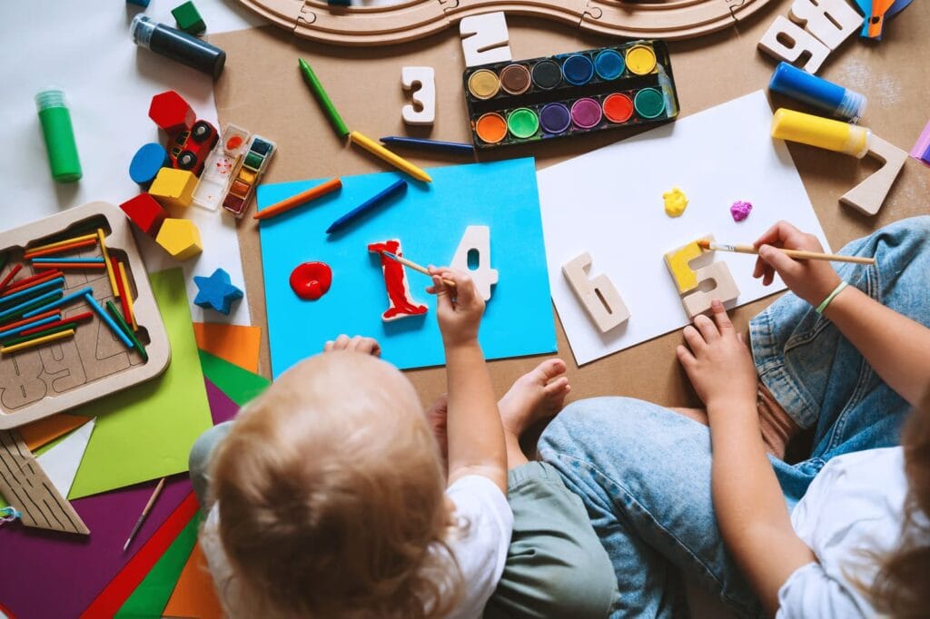 Children painting numbers and exploring colourful art supplies during a creative activity at a Langley daycare, supporting early learning and fine motor skills development.